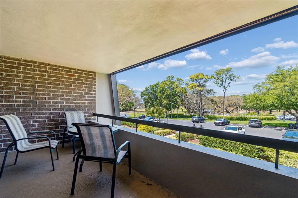 A balcony with two chairs, a brick wall, and a view of a parking lot — 36750 US HIGHWAY 19 N UNIT 22208, PALM HARBOR, FL