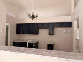 A kitchen features dark cabinets, light countertops, and a chandelier hanging from a vaulted ceiling — 20 PECAN COURSE WAY, OCALA, FL