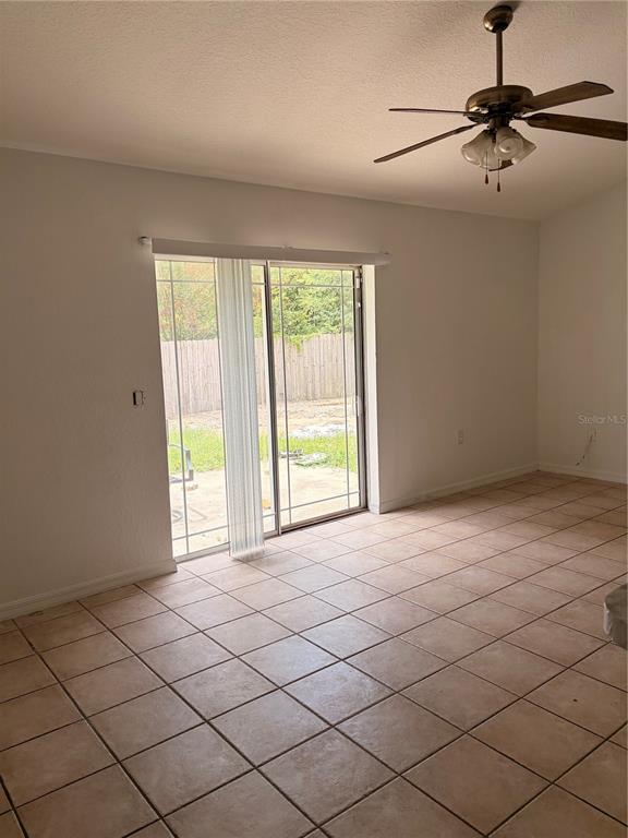 A room with light-colored tile flooring, a ceiling fan, and sliding glass doors to a yard — 20 PECAN COURSE WAY, OCALA, FL