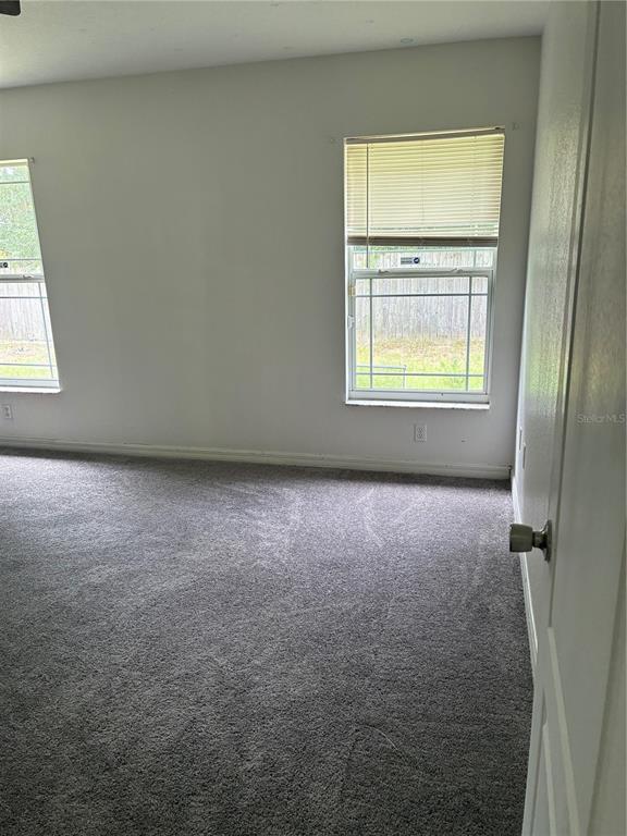 An empty bedroom features gray carpet, white walls, and two windows with horizontal blinds — 20 PECAN COURSE WAY, OCALA, FL
