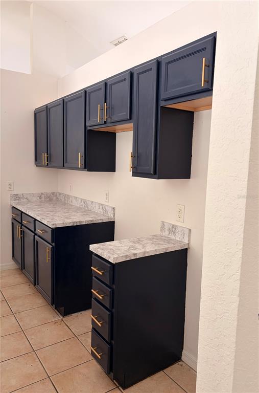 A kitchen features dark blue cabinets with gold hardware and light-colored marble-patterned countertops — 20 PECAN COURSE WAY, OCALA, FL