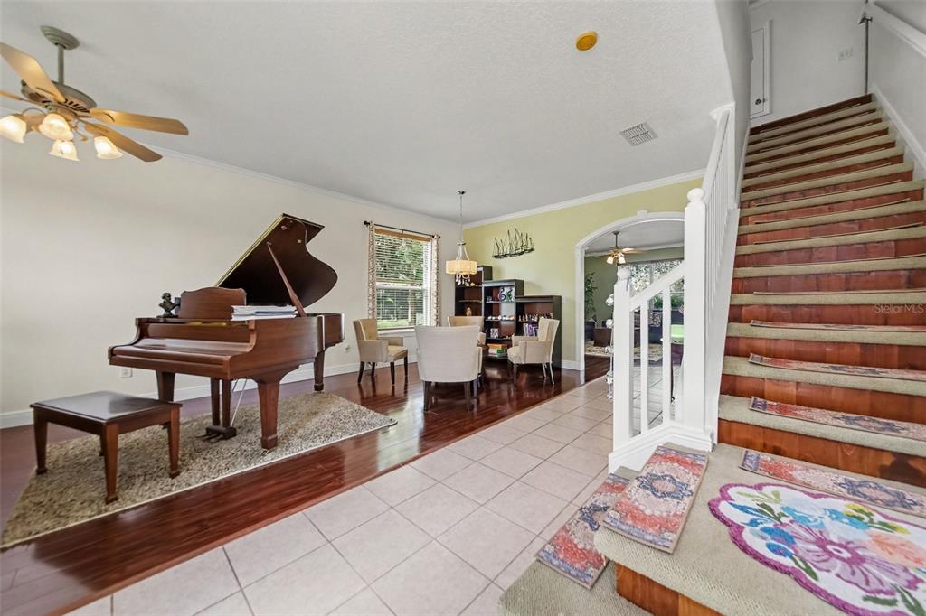 A grand piano sits on a hardwood floor next to a dining area and staircase — 246 BRIGHTVIEW DRIVE, LAKE MARY, FL