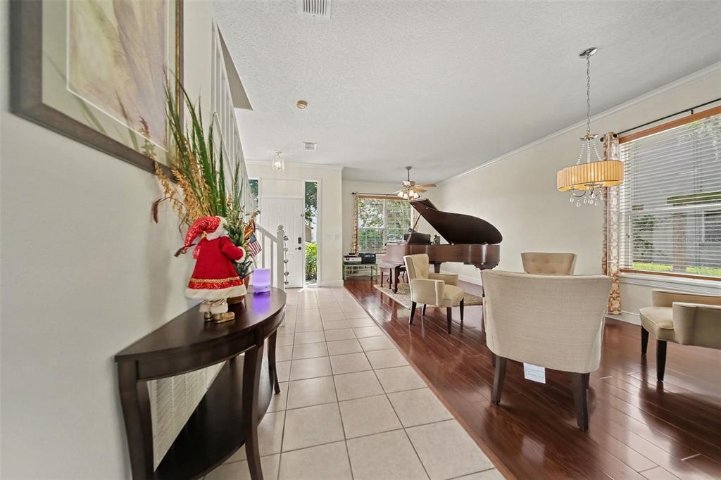 A dining area with a grand piano features tile and hardwood flooring and a chandelier — 246 BRIGHTVIEW DRIVE, LAKE MARY, FL