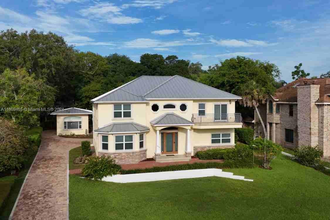 A two-story house with a metal roof, beige stucco exterior, and a brick driveway — 1613 N Indian River Drive, Cocoa FL 32922, COCOA, FL