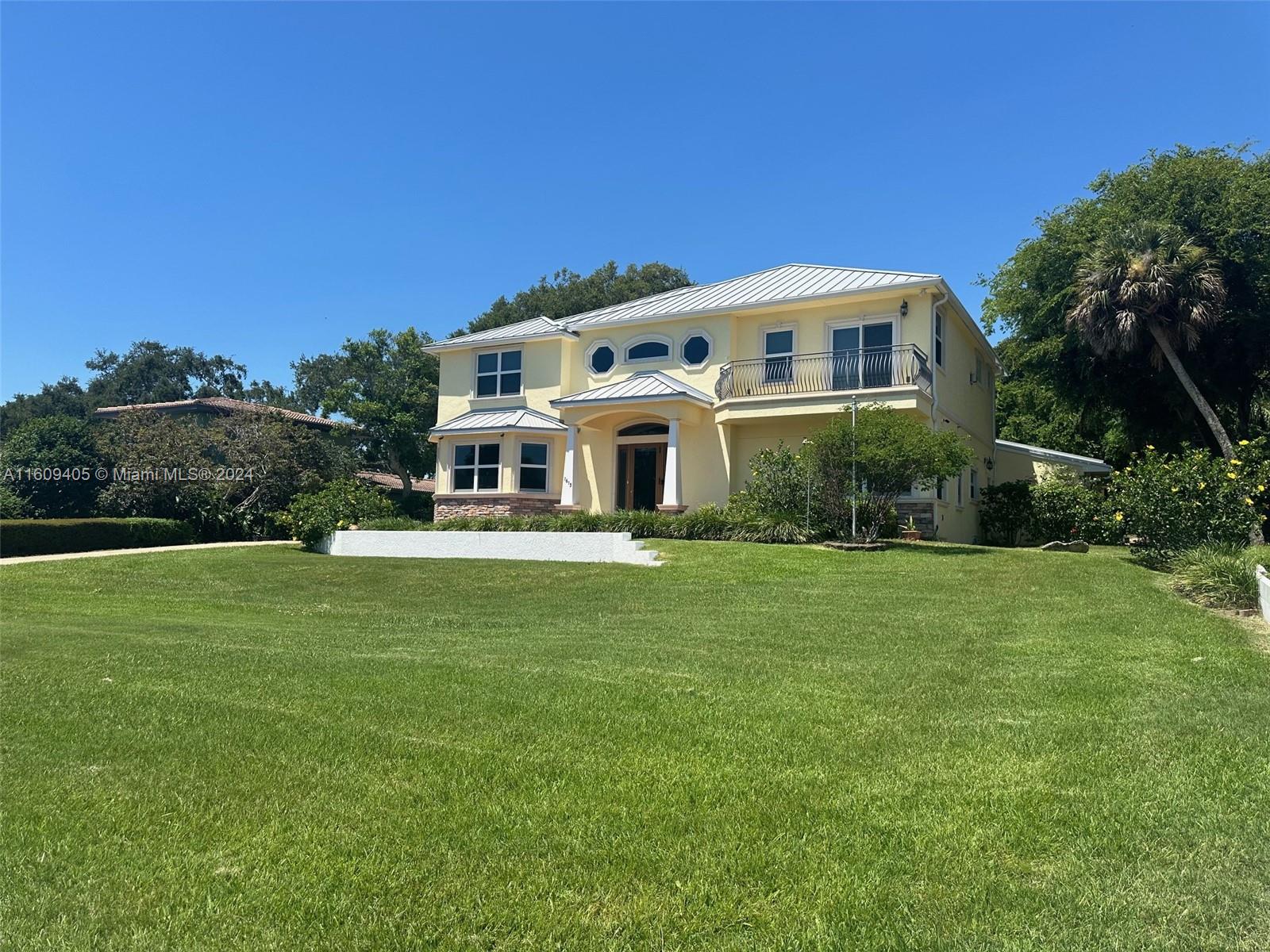 A two-story yellow house with a metal roof and a balcony sits on a lawn — 1613 N Indian River Drive, Cocoa FL 32922, COCOA, FL