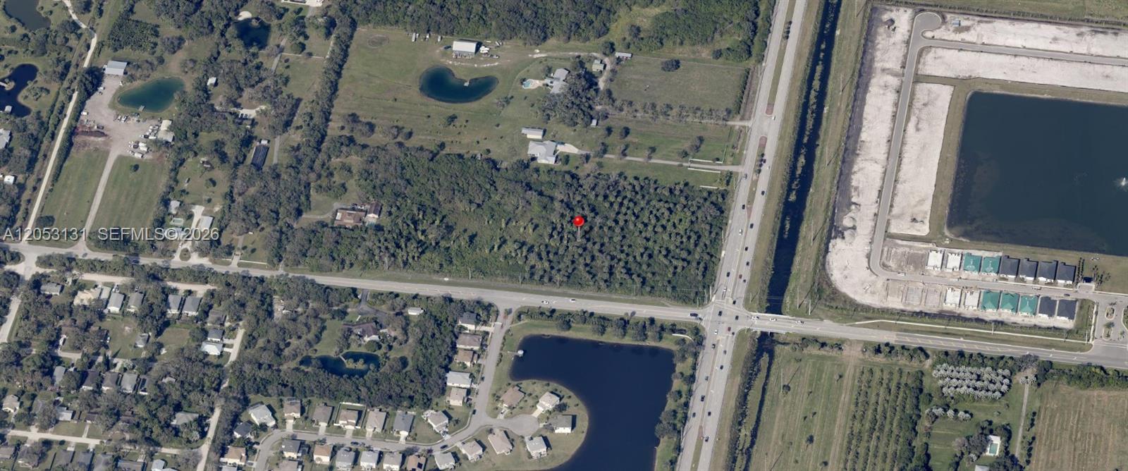 An aerial view shows a wooded lot marked with a red pin near a road — 5992 8th St, Vero Beach FL 32968, VERO BEACH, FL