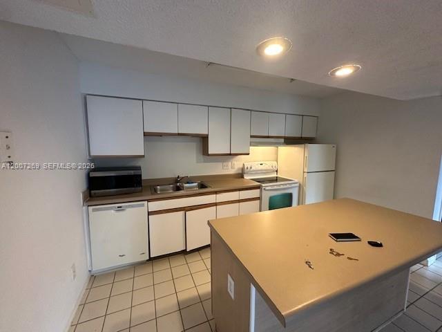 A kitchen features white cabinetry, a central island, a dishwasher, and a white refrigerator — 3985 W Mcnab Rd # A111, Pompano Beach FL 33069, POMPANO BEACH, FL
