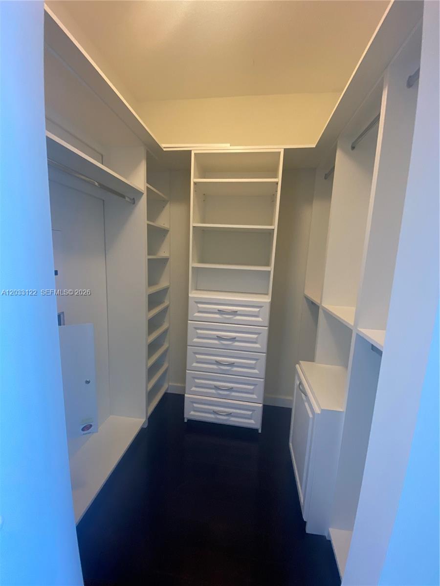 A walk-in closet features white shelving, a built-in dresser, and dark flooring — 185 SW 7th St # 4206, Miami FL 33130, MIAMI, FL