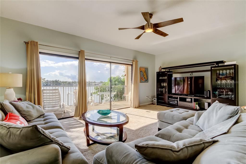 A living room features a sectional sofa, glass coffee table, media console, and sliding glass doors — 135 92ND AVENUE UNIT 5, TREASURE ISLAND, FL