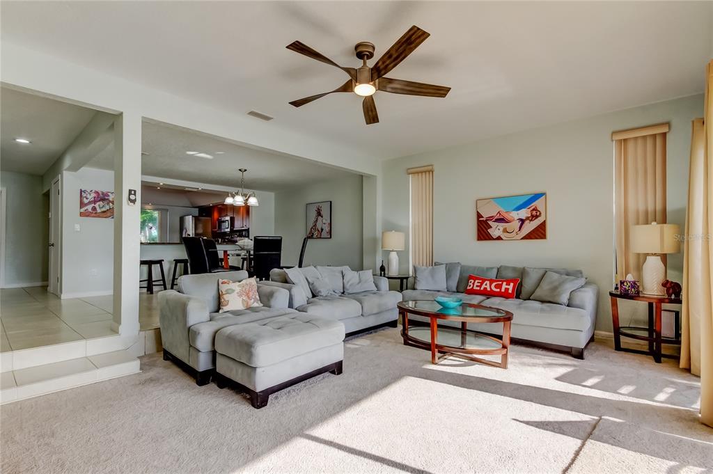 A living room with light gray sofas, a ceiling fan, and an open dining area — 135 92ND AVENUE UNIT 5, TREASURE ISLAND, FL