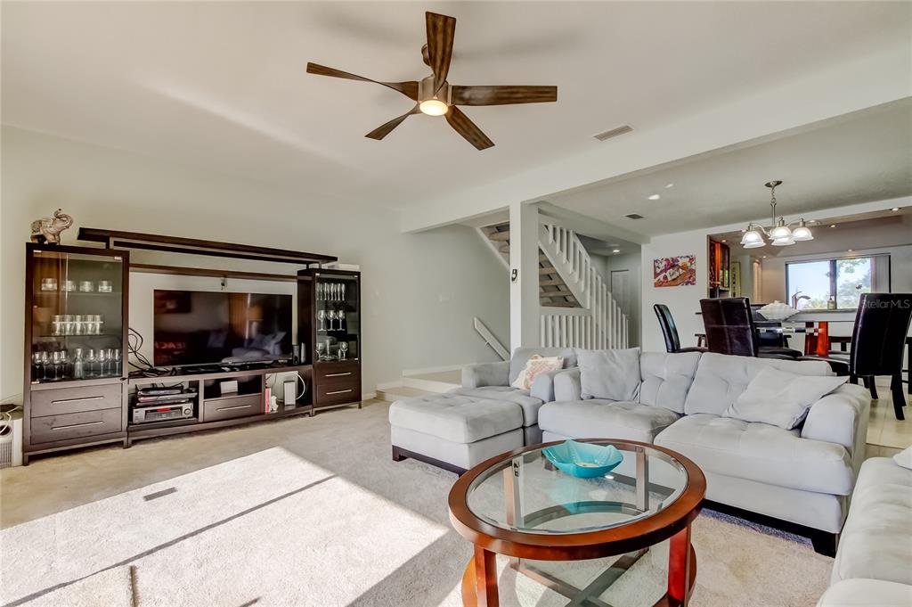 A living room features a sectional sofa, a glass coffee table, and a media console — 135 92ND AVENUE UNIT 5, TREASURE ISLAND, FL