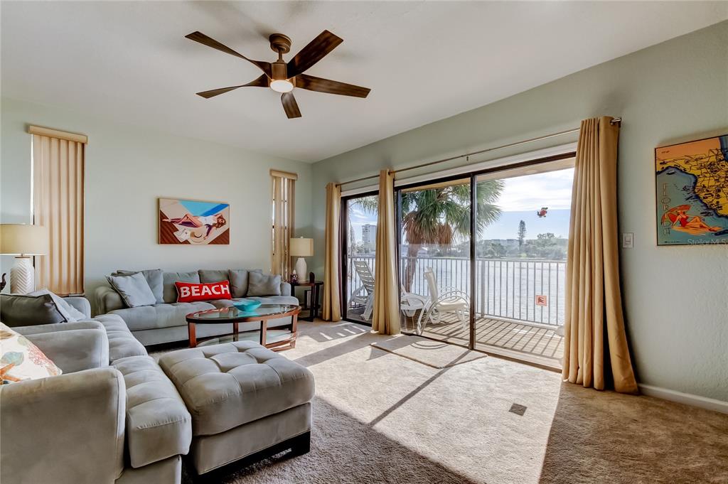 A living room features a gray sectional sofa, a ceiling fan, and a sliding glass door — 135 92ND AVENUE UNIT 5, TREASURE ISLAND, FL