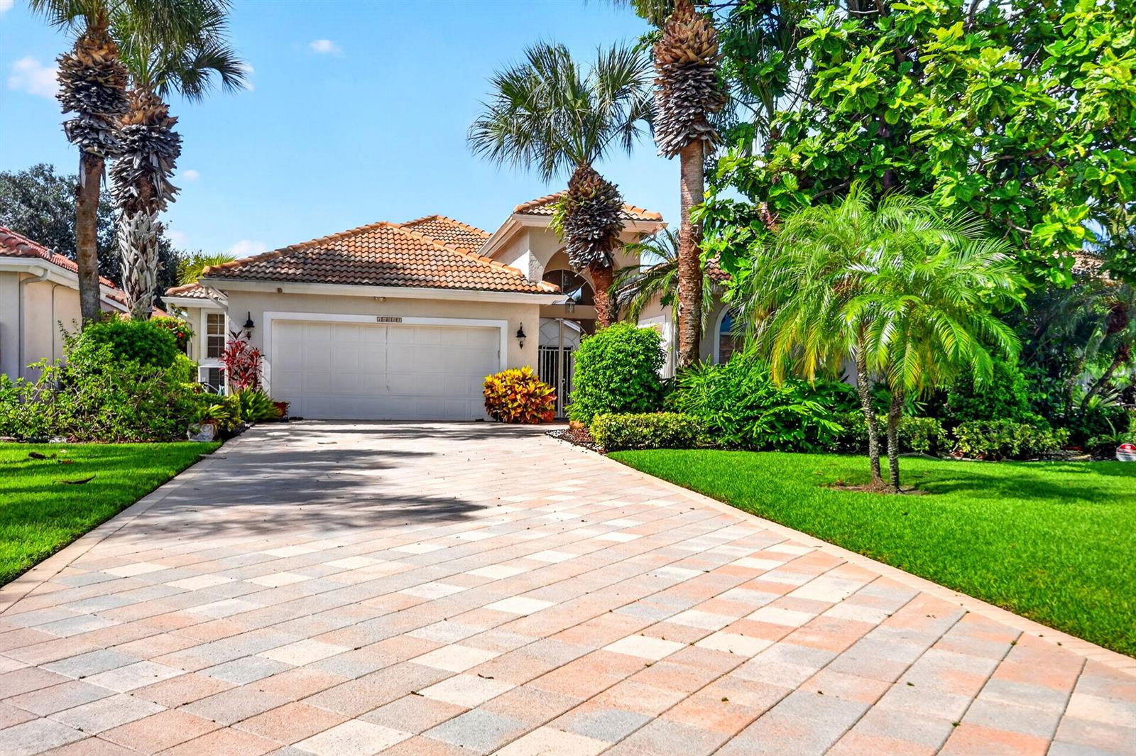 A single-story house with a tiled roof, a paved driveway, and lush tropical landscaping — 10694 Greenbriar Villa Drive, Lake Worth FL 33449, LAKE WORTH, FL