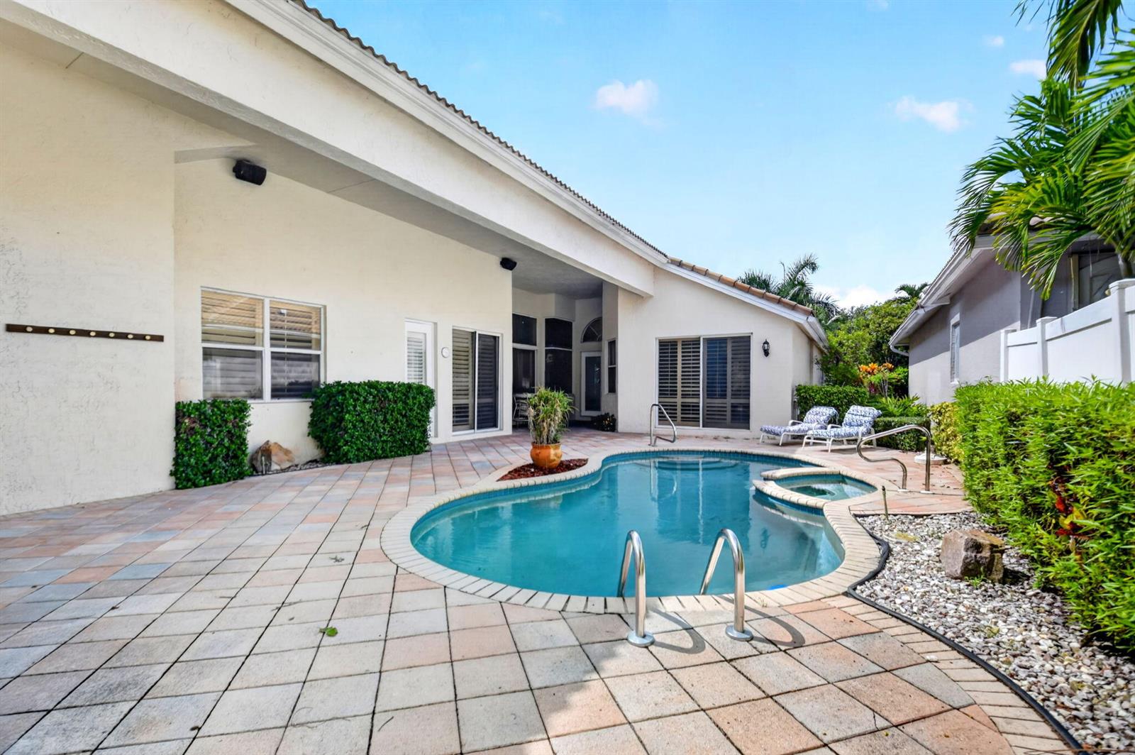 A backyard features a swimming pool with a spa, patio pavers, and a covered porch — 10694 Greenbriar Villa Drive, Lake Worth FL 33449, LAKE WORTH, FL