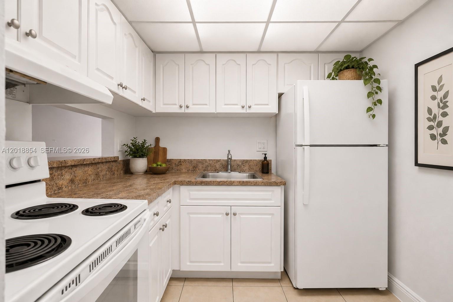 A small kitchen features white cabinets, a brown laminate countertop, and a white refrigerator — 9483 SW 76 St # N1, Miami FL 33173, MIAMI, FL