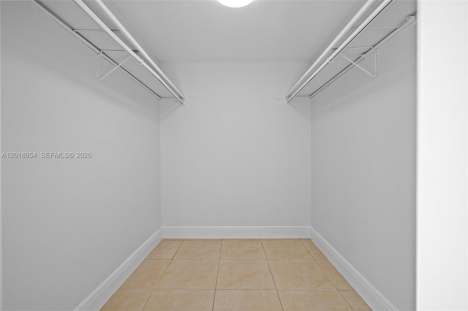 A walk-in closet features white walls, tile flooring, and two white wire shelving units — 9483 SW 76 St # N1, Miami FL 33173, MIAMI, FL