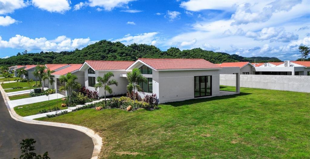 A modern, single-story house with a red tile roof sits on a grassy lot — 0 ISLA DE LAS FLORES, DORADO, PR