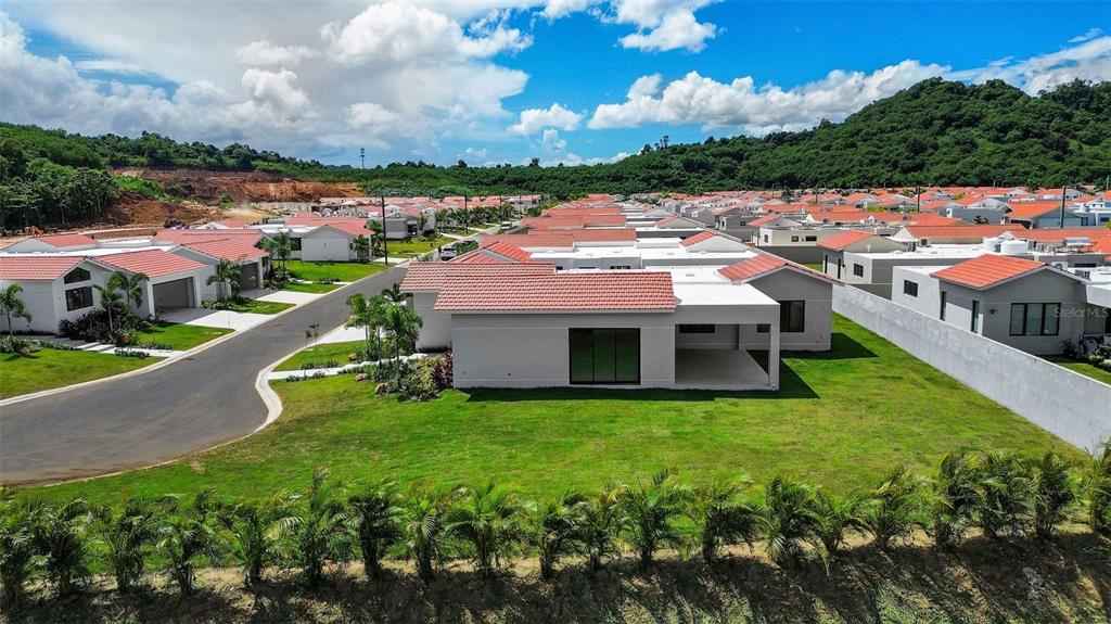 An aerial view shows a modern residential neighborhood with light-colored houses and red tile roofs — 0 ISLA DE LAS FLORES, DORADO, PR
