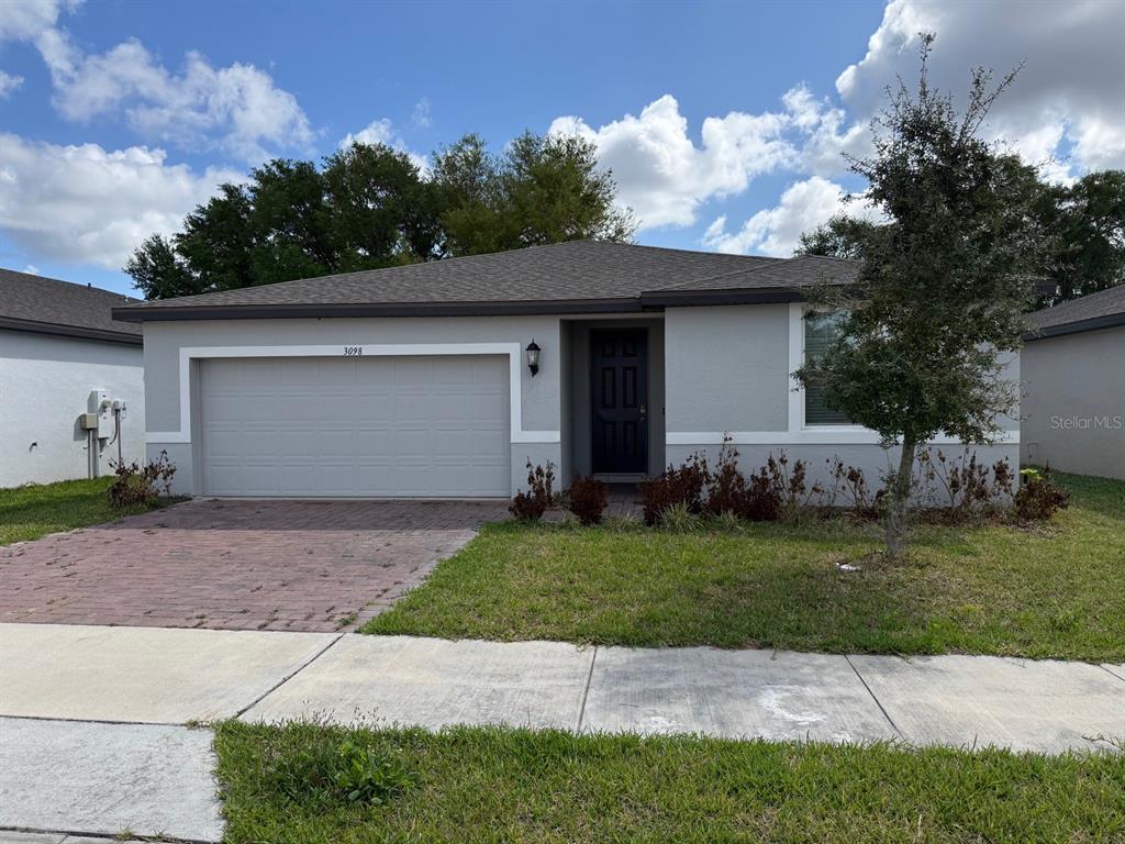 A single-story house with a gray exterior, a two-car garage, and a paved driveway — 3098 LAUREL OAK LANE, WINTER HAVEN, FL