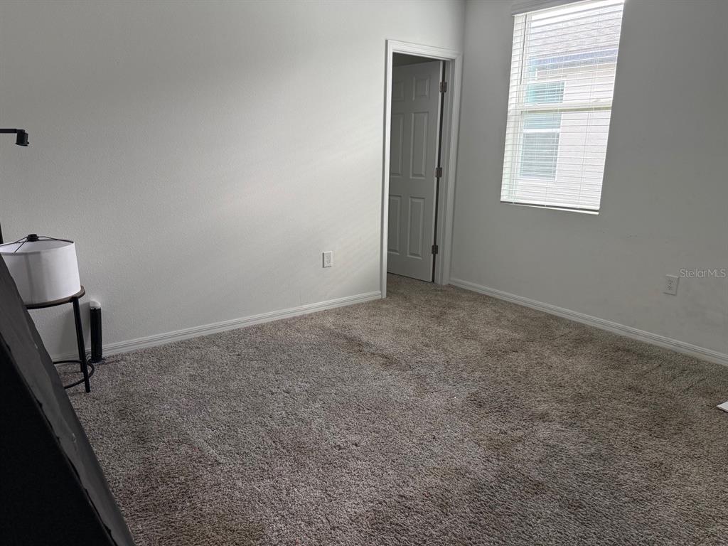 An empty bedroom features beige carpet, white walls, a window with blinds, and an open doorway — 3098 LAUREL OAK LANE, WINTER HAVEN, FL