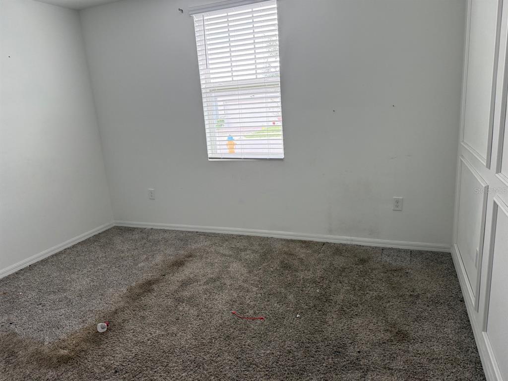 An empty bedroom features gray carpet, white walls, a single window, and a white closet — 3098 LAUREL OAK LANE, WINTER HAVEN, FL