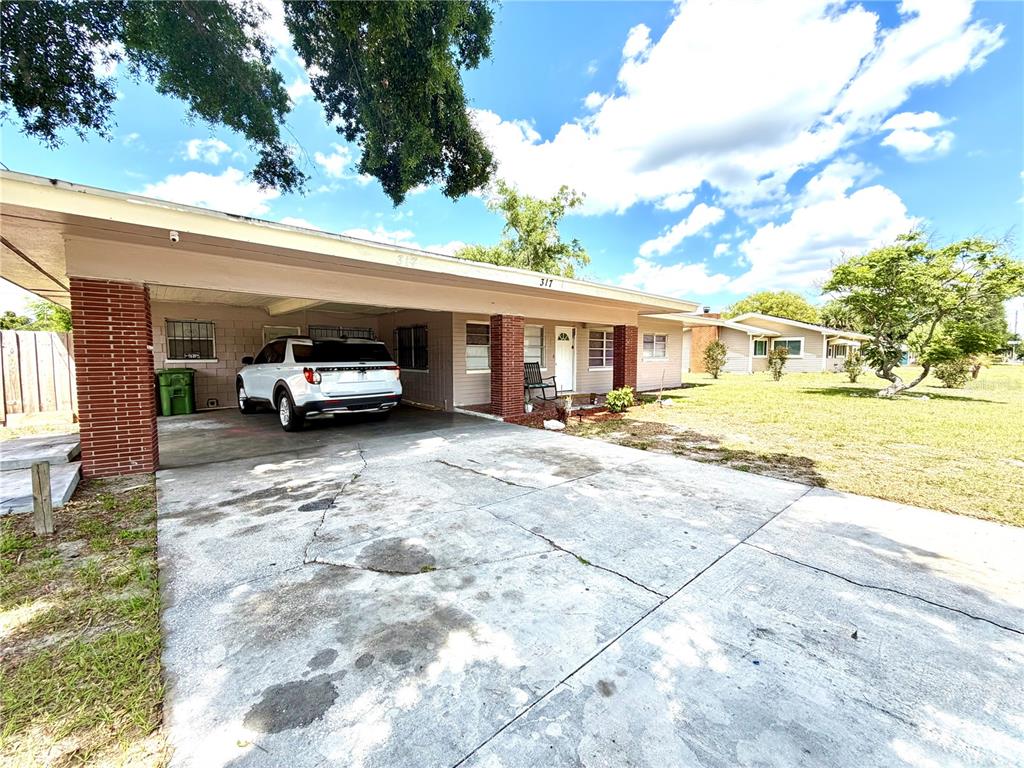 A single-story house with a carport, a concrete driveway, and a brick-accented front porch — 317 AVENUE G SE, WINTER HAVEN, FL
