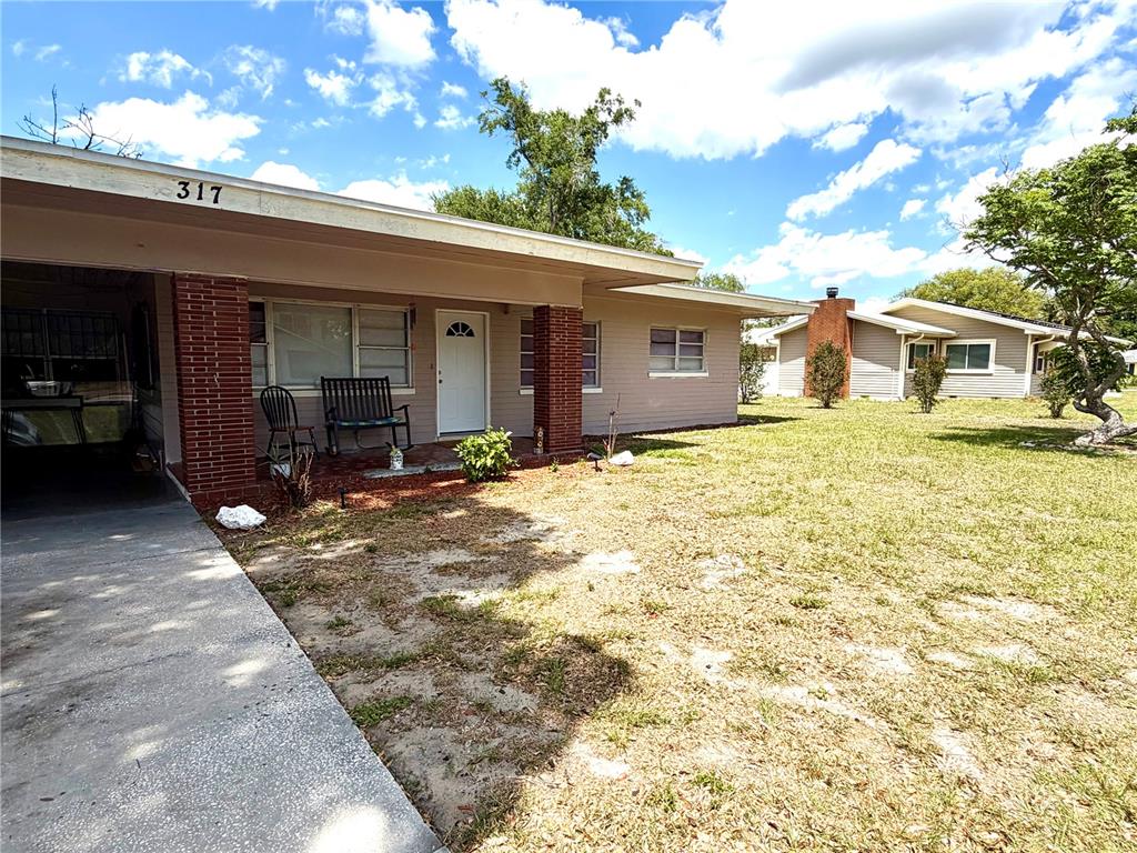 A single-story house with a brick-pillared porch, a concrete driveway, and a grassy front yard — 317 AVENUE G SE, WINTER HAVEN, FL