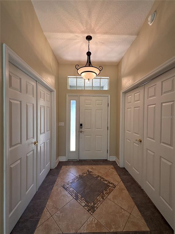 An entryway features a tiled floor with a decorative inlay, a chandelier, and white doors — 30 WILD FERN LANE, ORMOND BEACH, FL