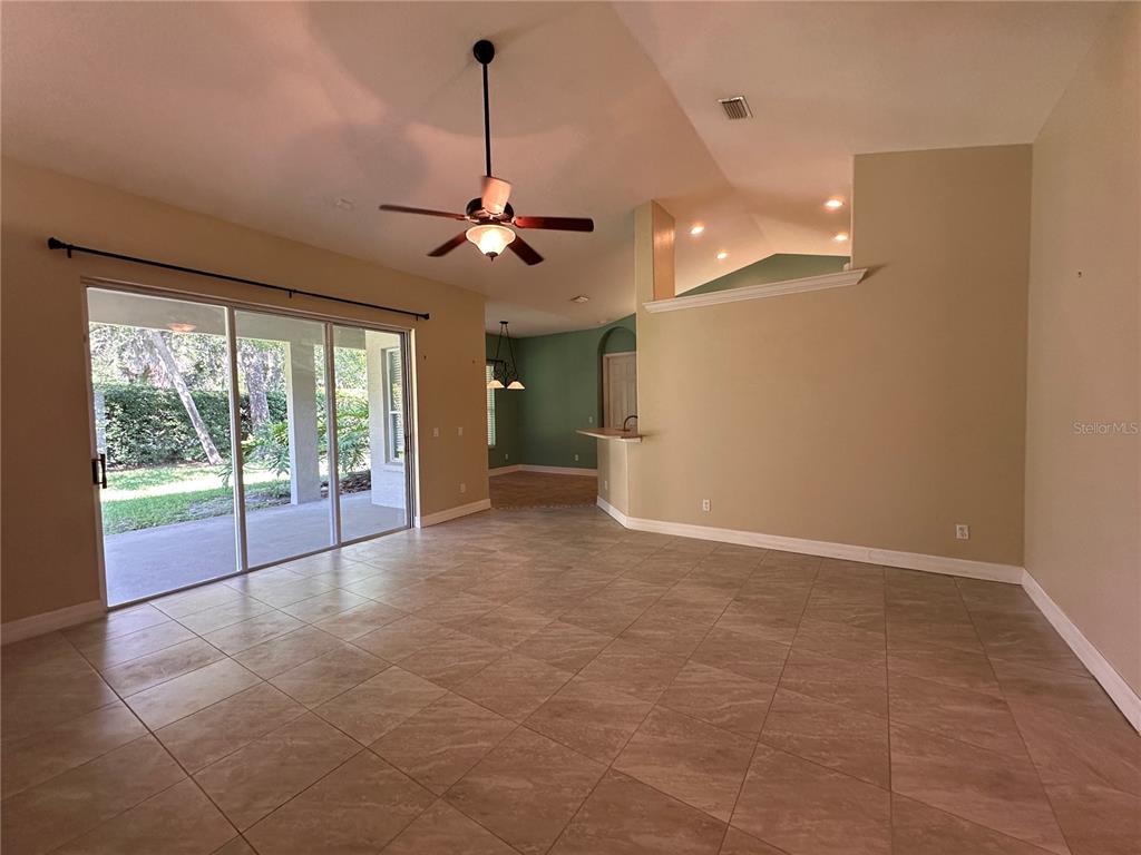 A tiled living room features a ceiling fan, sliding glass doors, and a breakfast bar — 30 WILD FERN LANE, ORMOND BEACH, FL