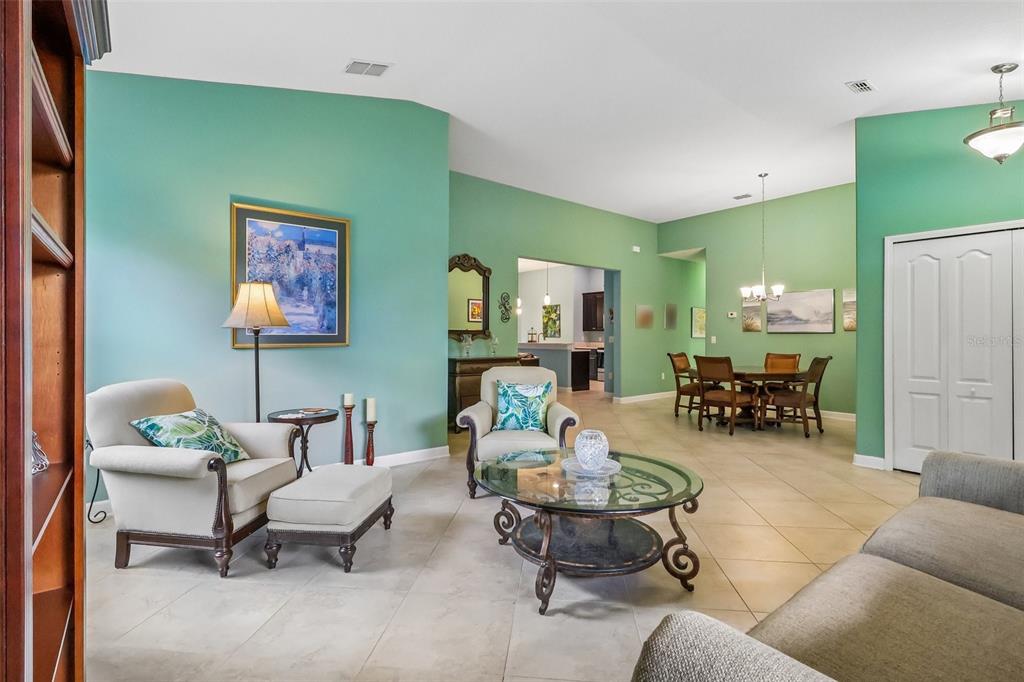 A living and dining area with light green walls, tile flooring, and vaulted ceilings — 8976 DOVE VALLEY WAY, DAVENPORT, FL