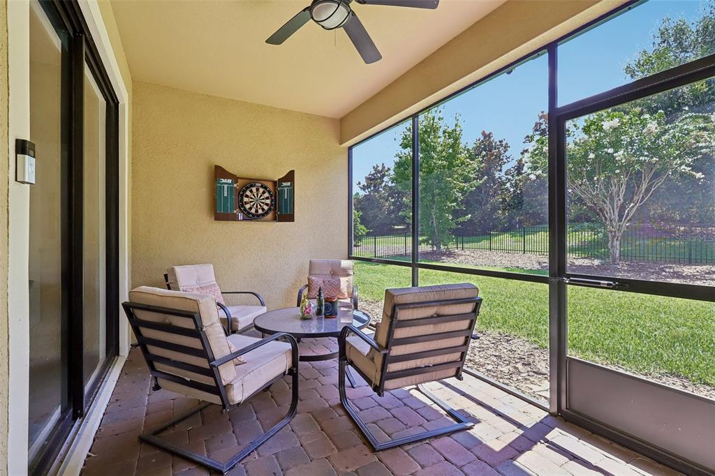 A screened-in patio with brick pavers, patio furniture, a dartboard, and a view of grass — 8976 DOVE VALLEY WAY, DAVENPORT, FL