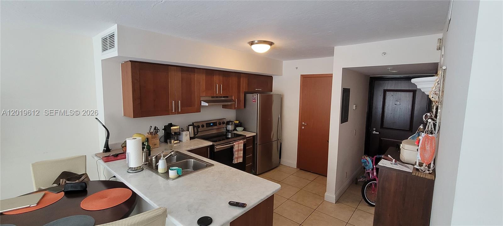 A kitchen features wood cabinets, stainless steel appliances, and a white countertop island — 9499 Collins Ave # 705, Surfside FL 33154, SURFSIDE, FL