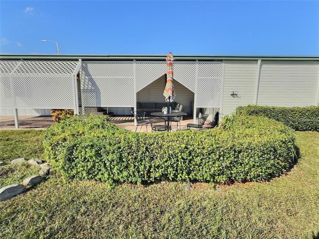 A patio with outdoor furniture sits behind a hedge in front of a house — 667 SUGAR PALM STREET, LARGO, FL