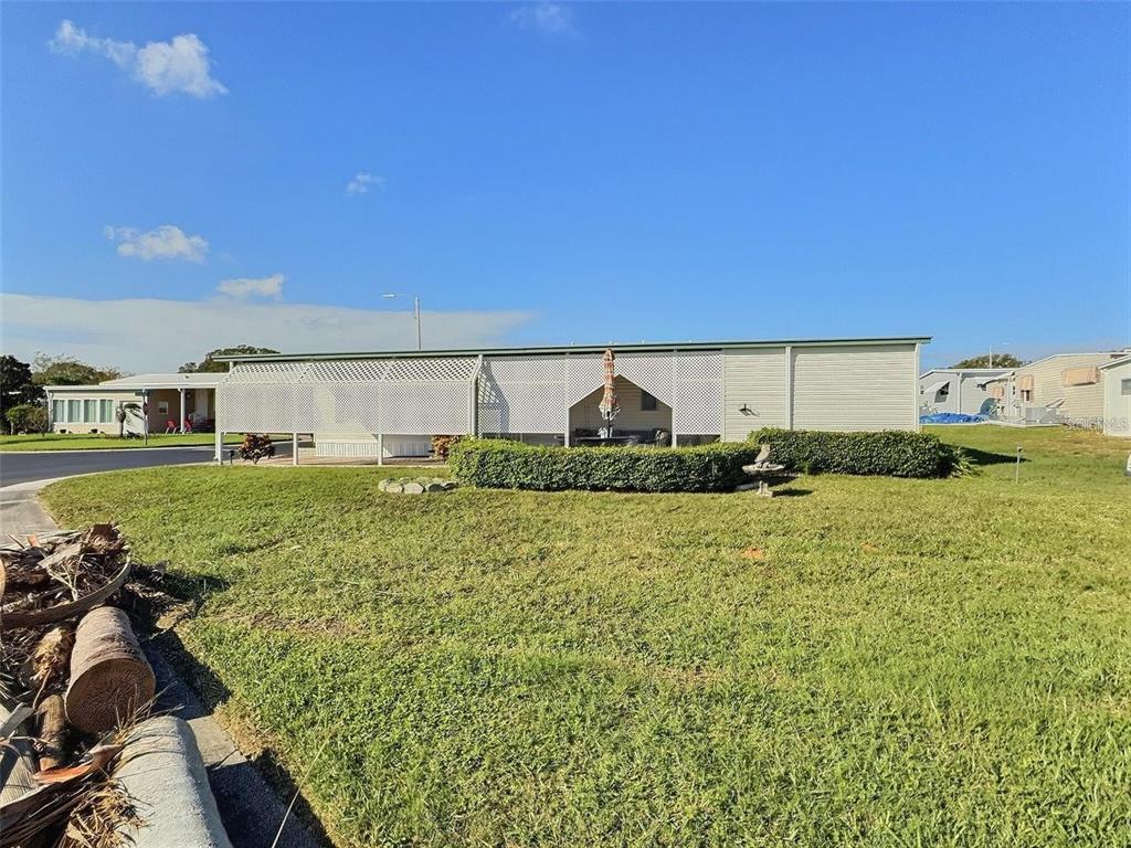 A single-story manufactured home with a lattice-enclosed porch and a large front lawn — 667 SUGAR PALM STREET, LARGO, FL
