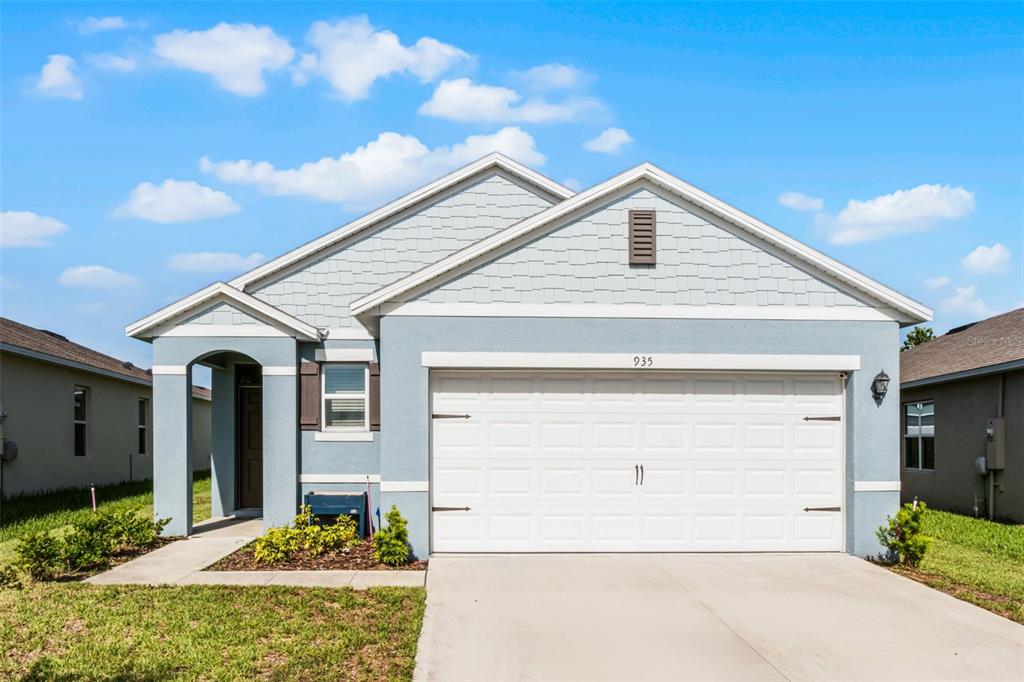 A light blue single-story house features a two-car garage and a small covered entryway — 935 AUGUST SKY DRIVE, DELTONA, FL
