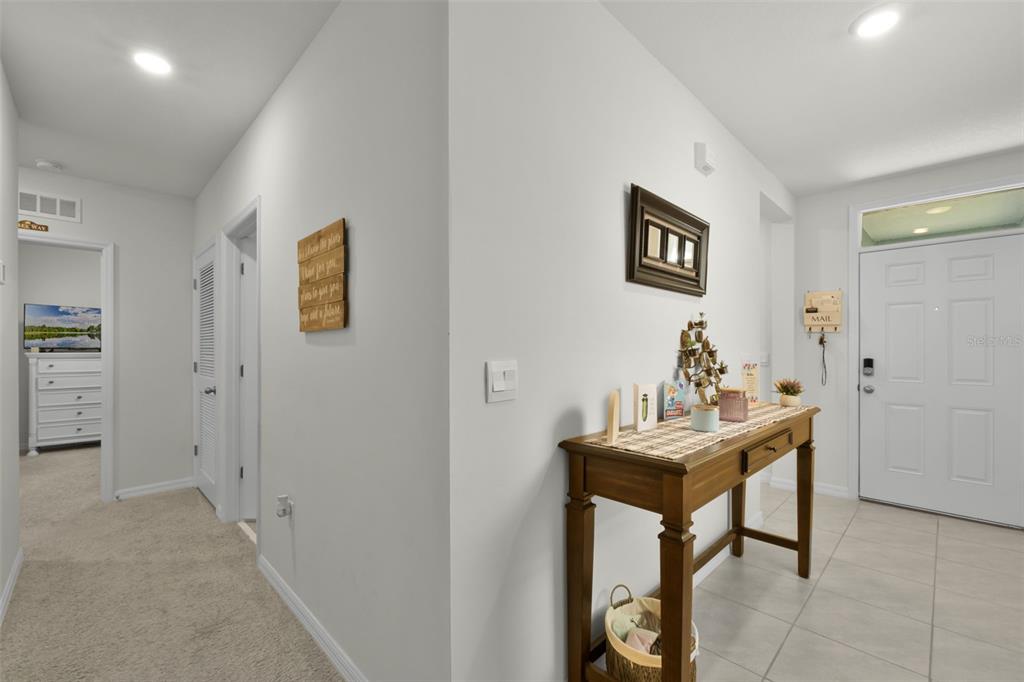 A white-walled entryway features a console table with a lamp, decor, and tile flooring — 935 AUGUST SKY DRIVE, DELTONA, FL
