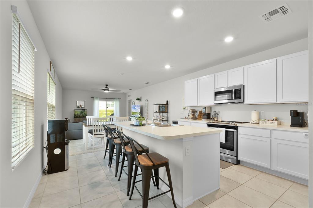 A living room features light gray furniture, a patterned rug, and a sliding glass door — 935 AUGUST SKY DRIVE, DELTONA, FL