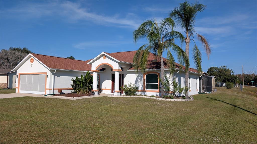 A single-story house with a white stucco exterior, orange trim, and two palm trees — 858 MENDOZA DRIVE, KISSIMMEE, FL
