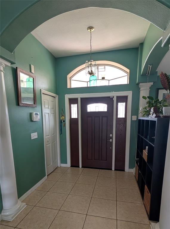 An entryway features teal walls, tile flooring, a dark wood front door, and arched architectural details — 858 MENDOZA DRIVE, KISSIMMEE, FL