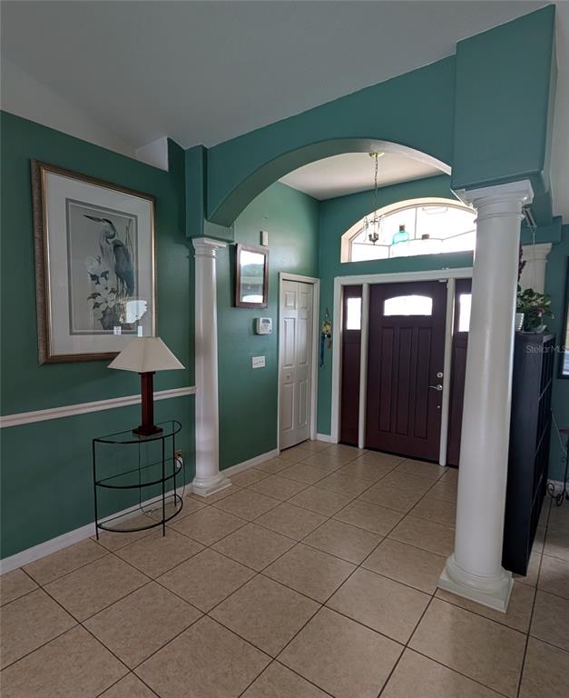An entryway features tile flooring, teal walls, white columns, and a dark wood front door — 858 MENDOZA DRIVE, KISSIMMEE, FL