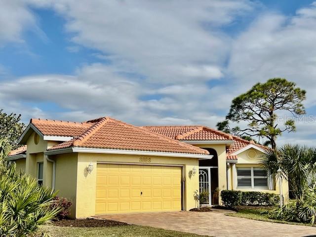 A single-story house with a yellow exterior, a two-car garage, and a tiled roof — 3893 CAPE COLE BOULEVARD, PUNTA GORDA, FL