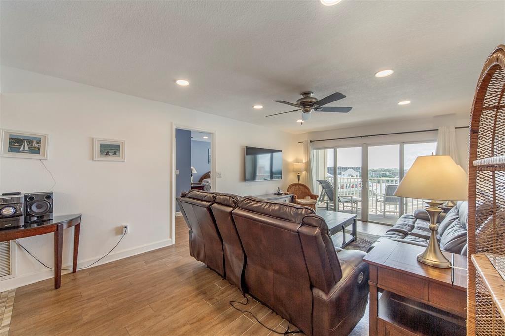 A living room features brown leather sofas, a ceiling fan, and a balcony with views — 12901 GULF LANE UNIT 503, MADEIRA BEACH, FL