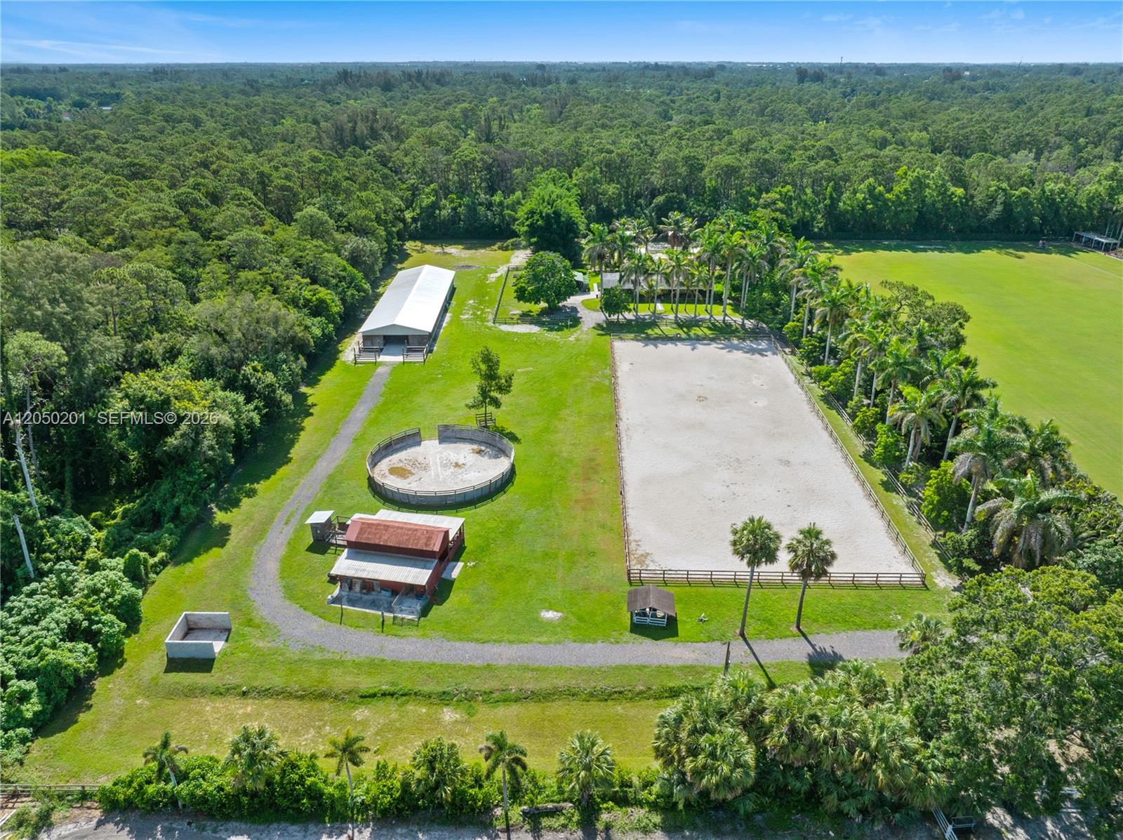 An aerial view shows an equestrian property with a riding arena, round pen, and barns — 1068 D Rd, Loxahatchee FL 33470, LOXAHATCHEE, FL