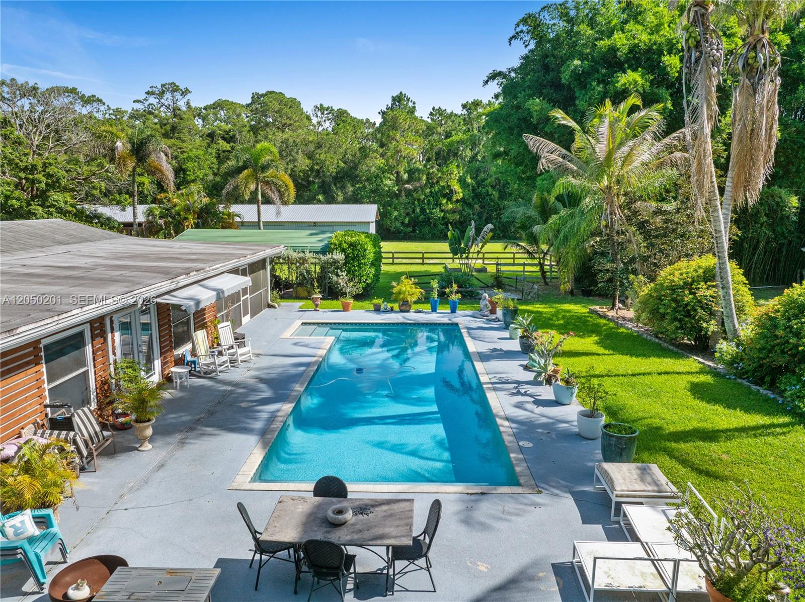 An aerial view shows a rectangular swimming pool on a patio next to a house — 1068 D Rd, Loxahatchee FL 33470, LOXAHATCHEE, FL