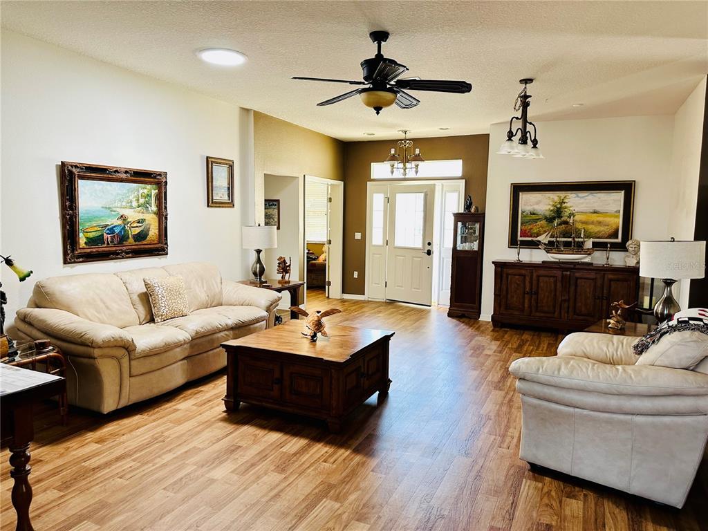 A living room features light-colored sofas, a wooden coffee table, and wood-look flooring — 9053 SW 103RD AVENUE, OCALA, FL