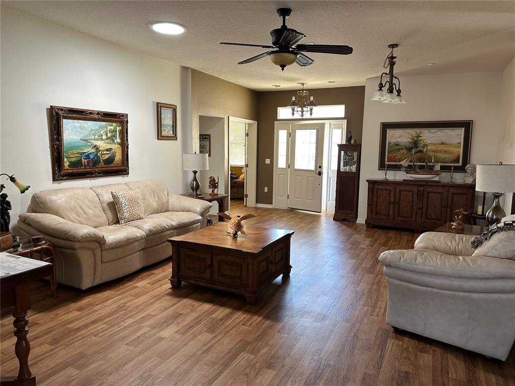 A living room features light-colored leather sofas, a wooden coffee table, and wood-look flooring — 9053 SW 103RD AVENUE, OCALA, FL