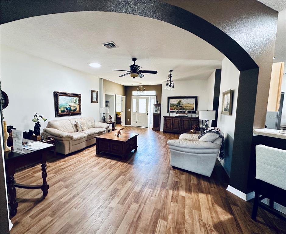 A living room features wood-look flooring, a ceiling fan, and an arched entryway — 9053 SW 103RD AVENUE, OCALA, FL