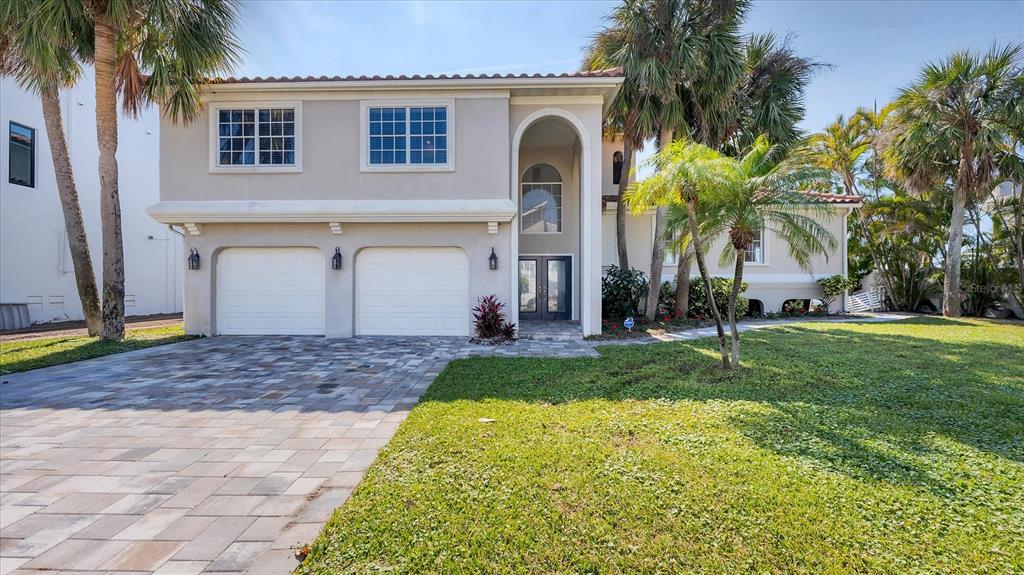 A two-story house with a two-car garage, arched entryway, and palm trees in the yard — 120 SANDS POINT DRIVE, TIERRA VERDE, FL