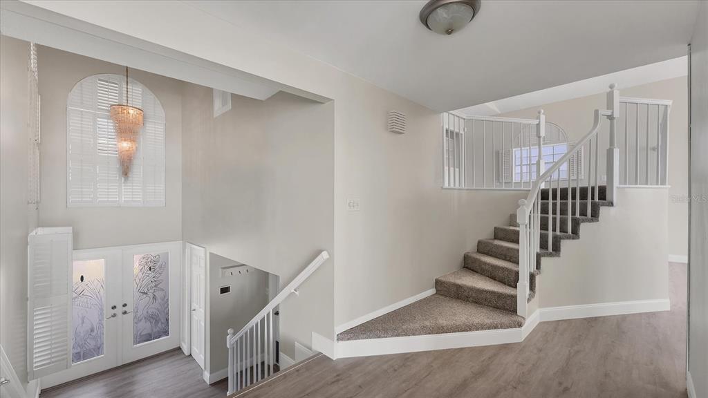 An entryway featuring a staircase with gray carpet, white railings, and a crystal chandelier — 120 SANDS POINT DRIVE, TIERRA VERDE, FL