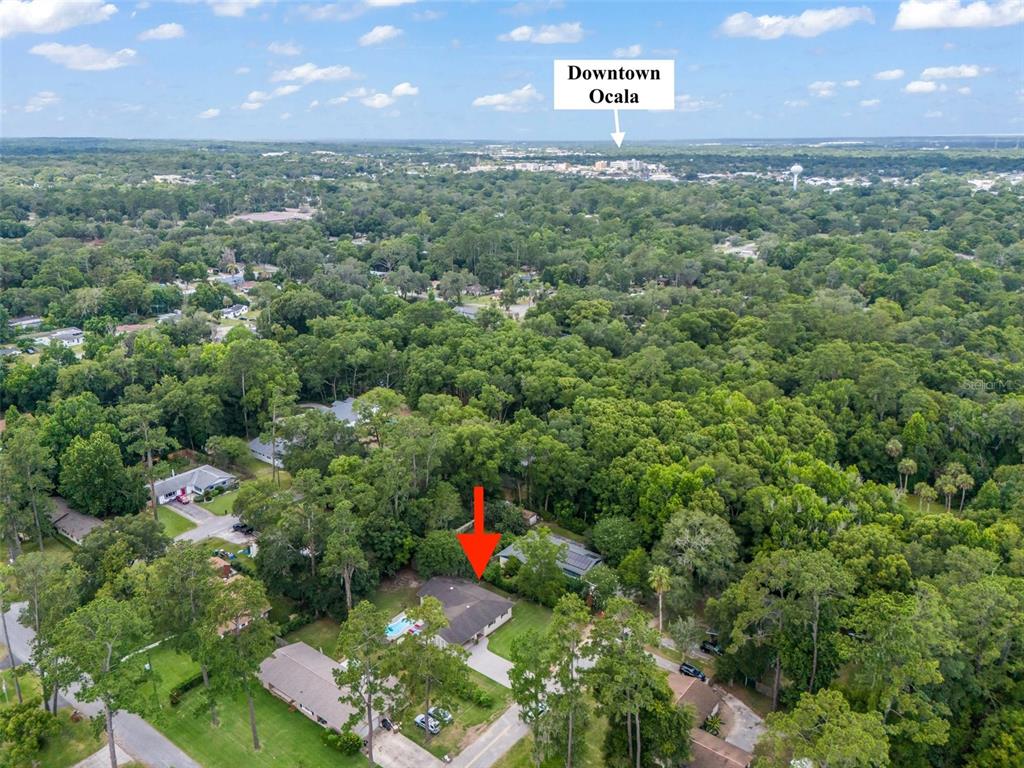 An aerial view shows a residential house with a pool surrounded by dense trees — 1520 NE 12TH STREET, OCALA, FL